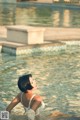 A woman in a white bathing suit sitting in a pool.