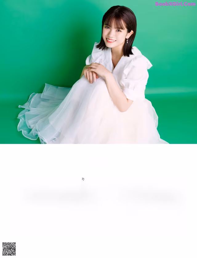 A woman in a white dress sitting on a green background.