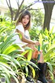 A woman sitting in the middle of a lush green garden.