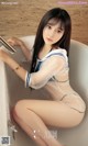 A woman sitting in a bathtub in a white and blue outfit.