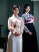 A couple of women standing next to each other in hanbok.