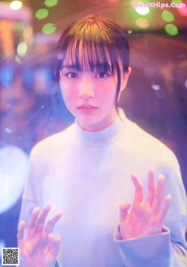 A woman in a white shirt is holding her hands up.