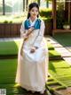 A woman in a white and blue hanbok is posing for a picture.