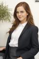 A woman in a suit and glasses sitting on a chair.