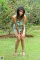 A woman in shorts and a tank top posing in the grass.