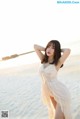 A woman in a white dress standing on a beach.