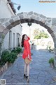 A woman in a red polka dot dress is standing in an archway.