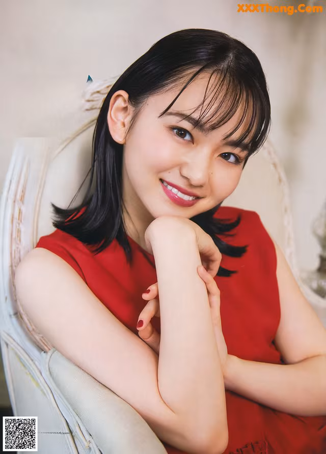 A woman in a red dress sitting on a white chair.