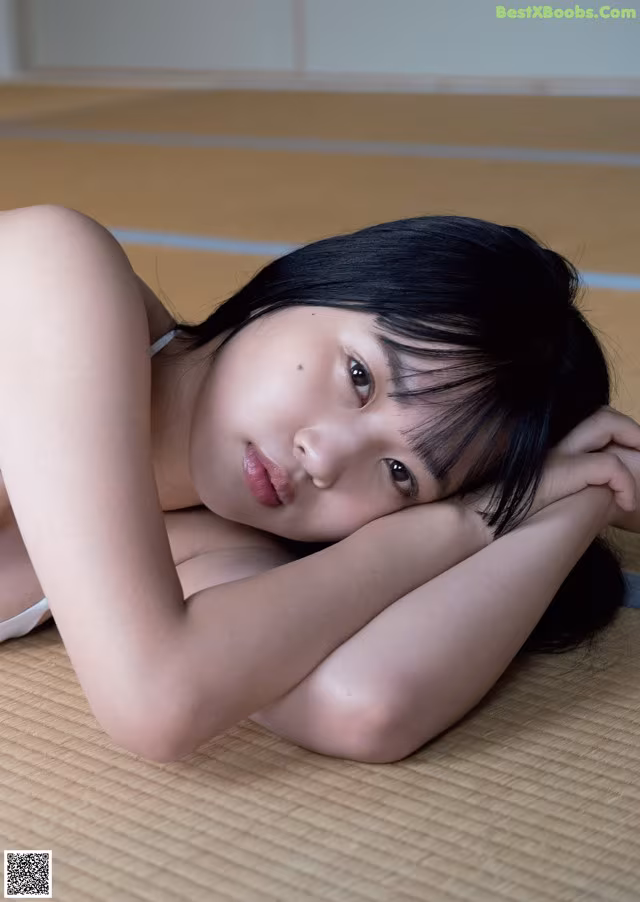 A woman laying on the floor with her head resting on her hands.