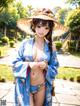 A woman in a blue kimono and a straw hat posing for a picture.