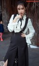 A woman in a white blouse and black skirt posing for a picture.