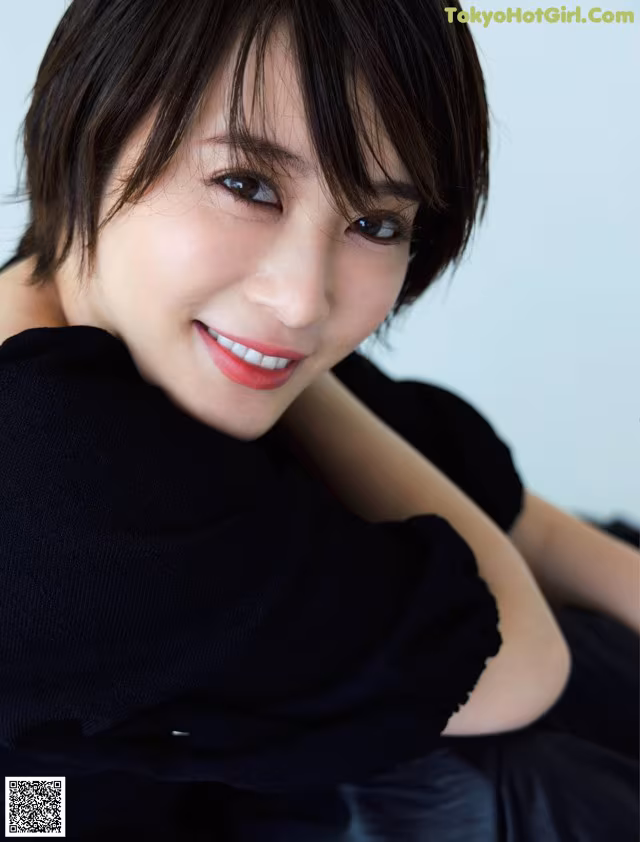 A woman in a black dress posing for a picture.