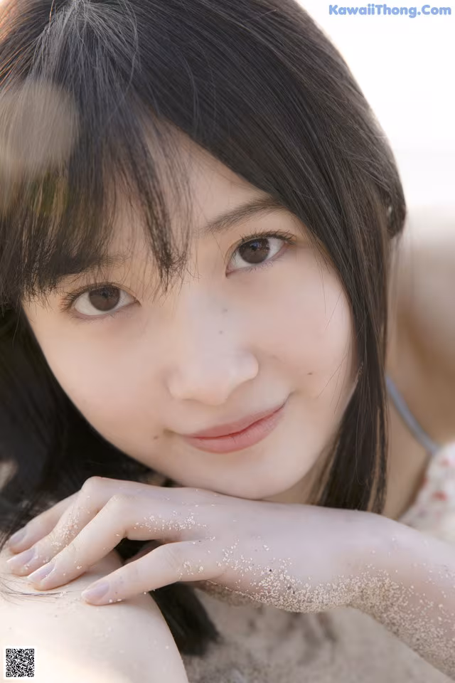A young woman laying in the sand on a beach.