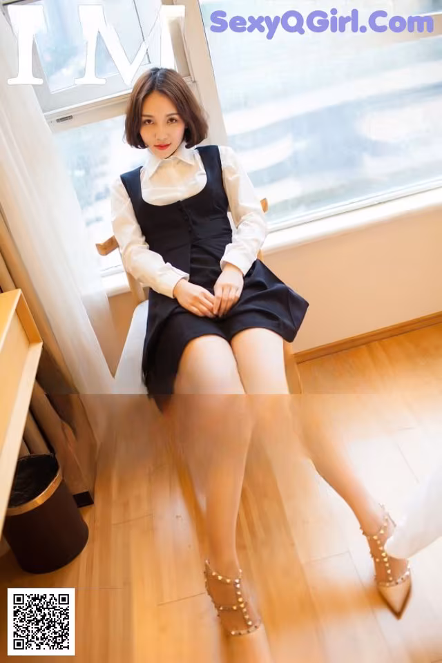 A woman sitting on a chair in front of a window.