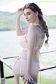 A woman in a pink bikini standing on a railing by the water.