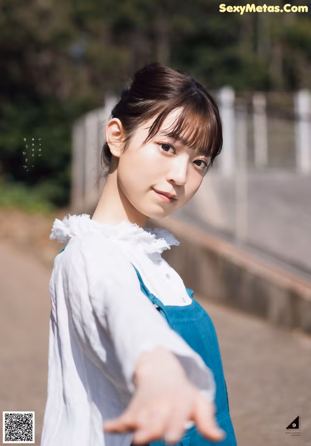 A woman in a white shirt and blue apron posing for a picture.