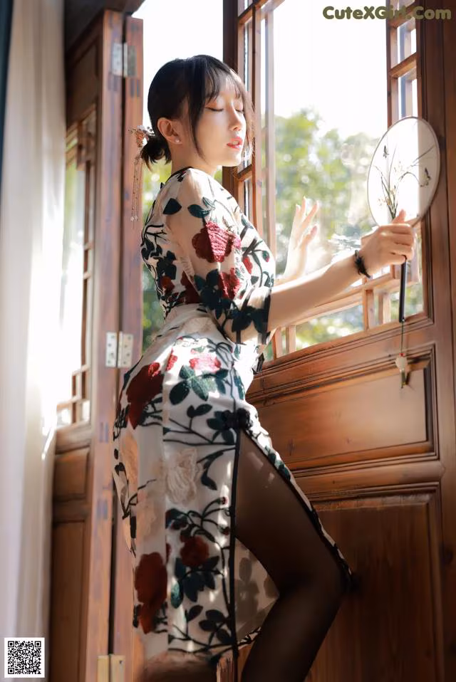 A woman in a kimono leaning against a window.