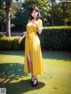 A woman in a yellow dress standing in a park.