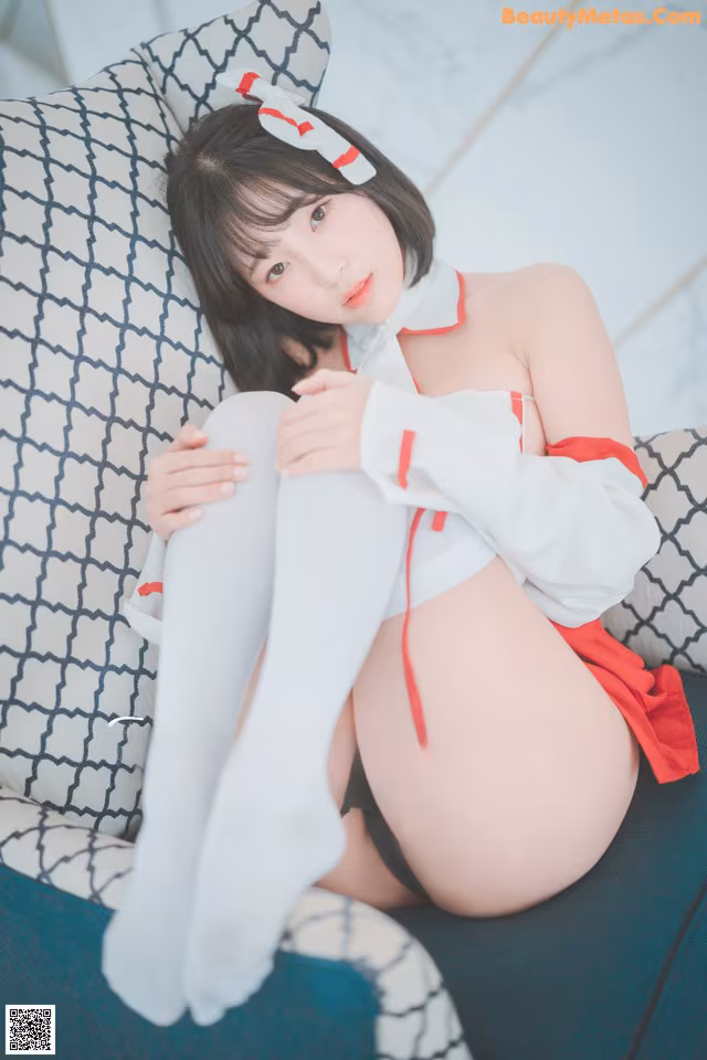 A woman in a white and red outfit sitting on a blue couch.