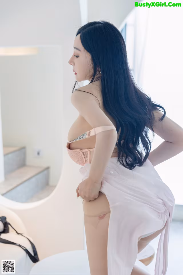 A woman in a pink lingerie posing in front of a mirror.