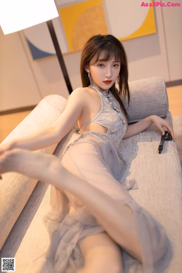 a woman laying on top of a couch next to a lamp