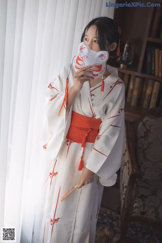 A woman in a white and red kimono holding a fan.